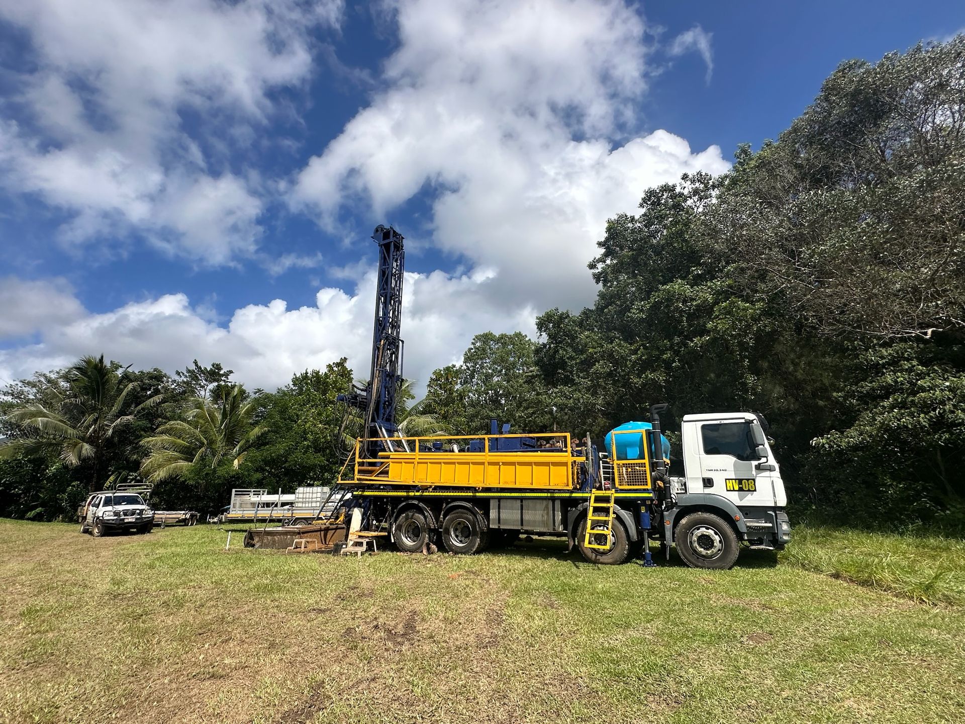 Drill rig set up on grass under a big tropical sky