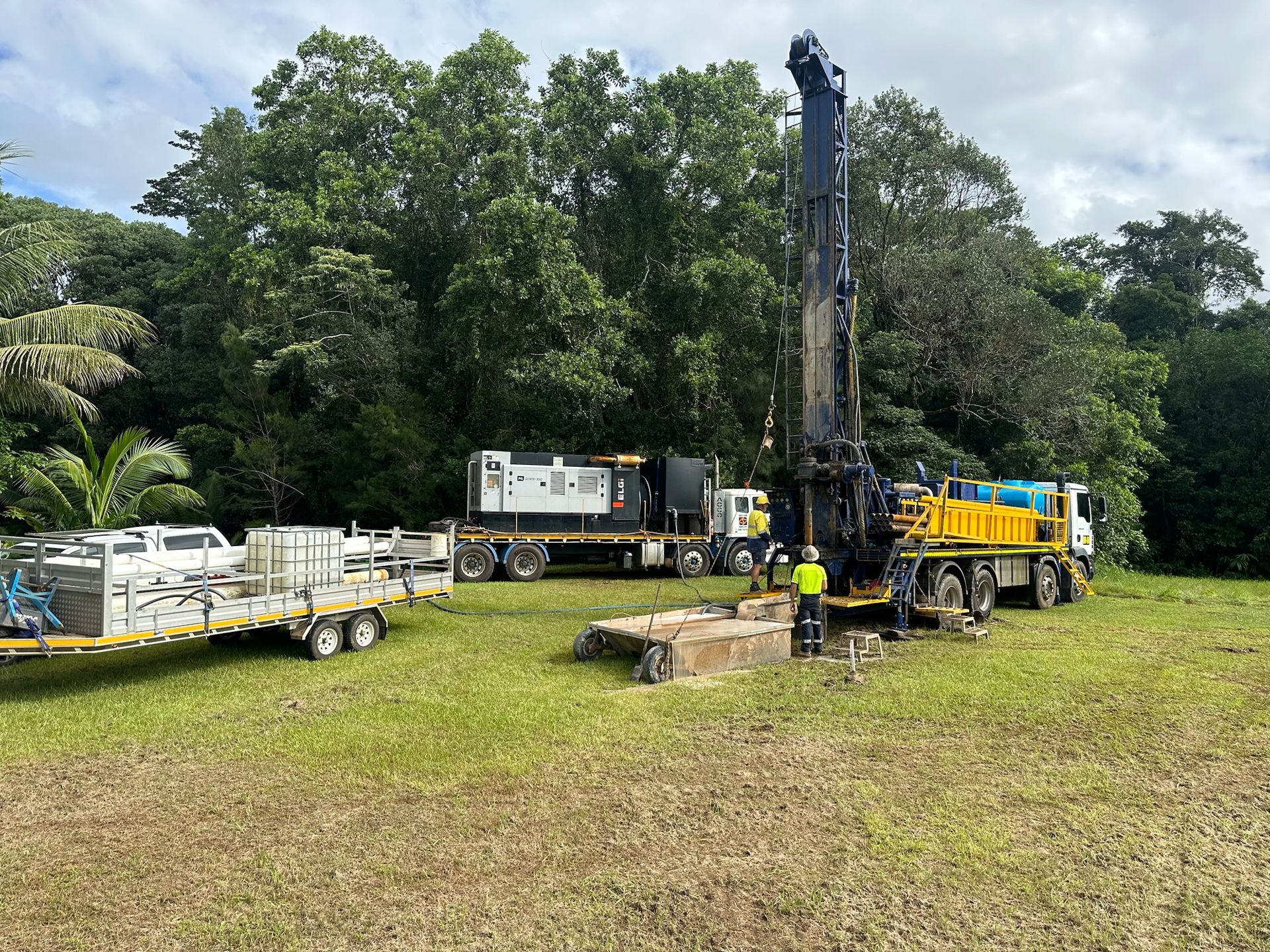 Crew setting up the rig and compressor truck beside rainforest