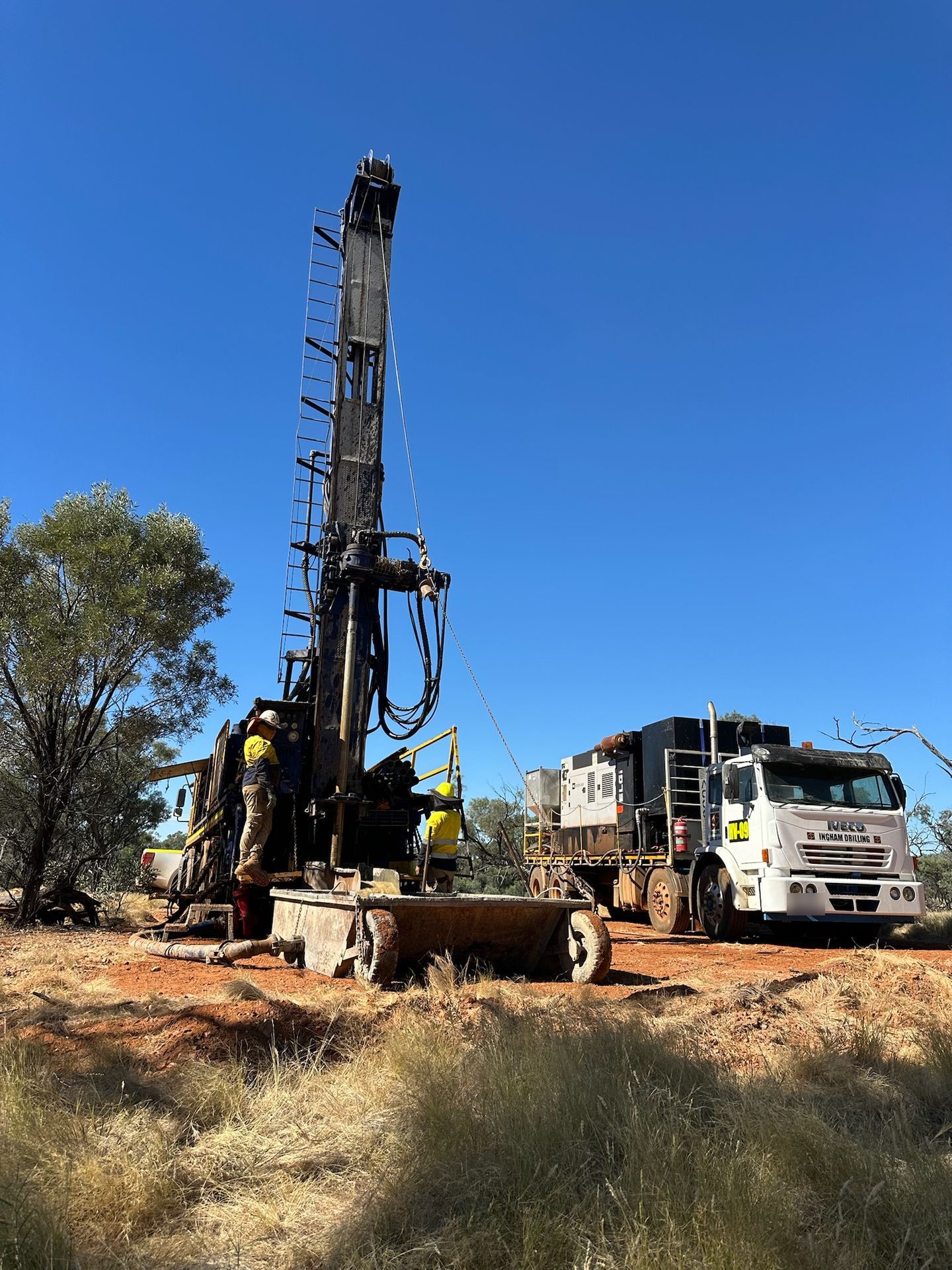 Crew working on the rig deck in dry country, with an Iveco support truck behind