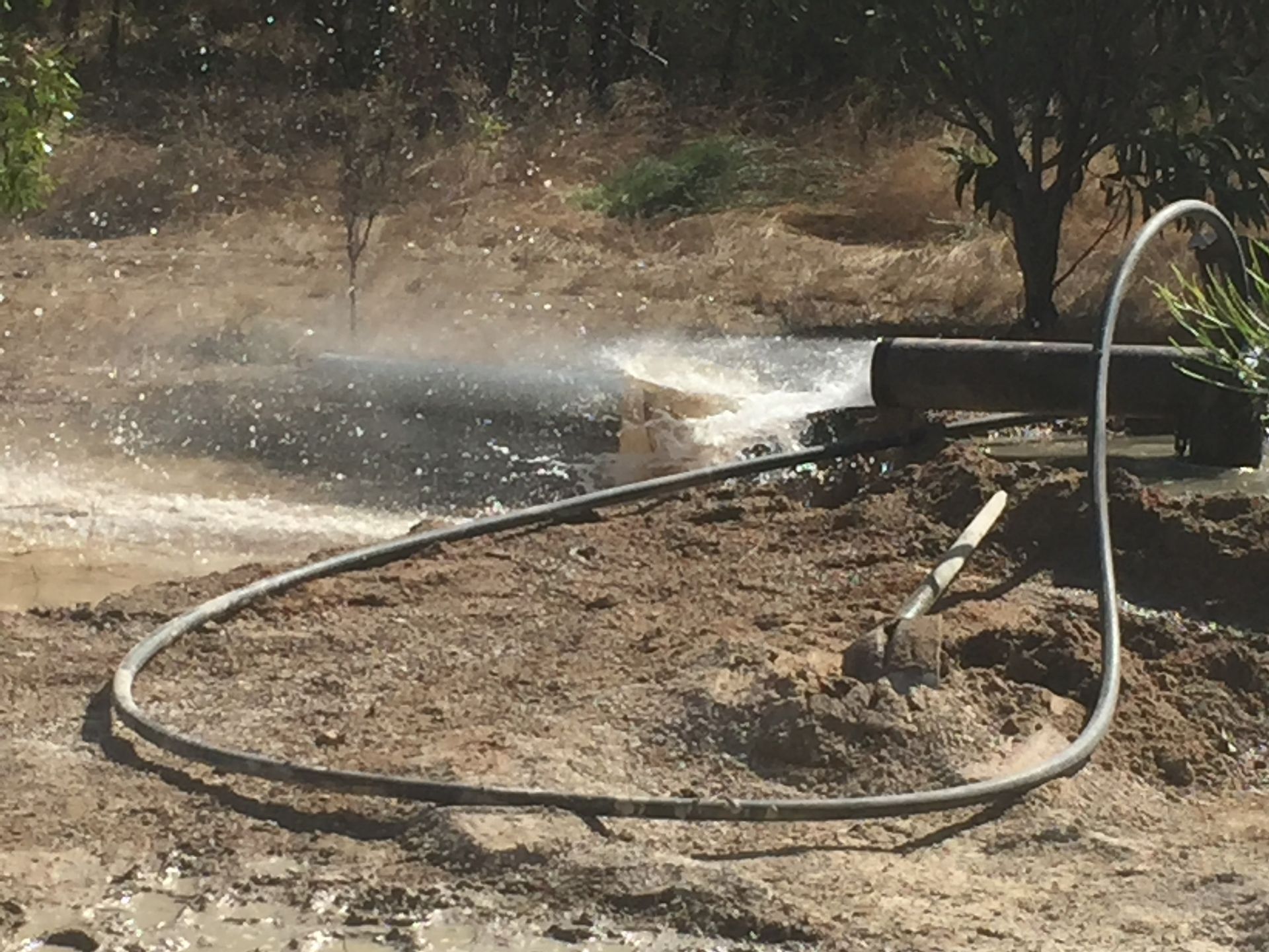 Water and air blowing out of a pipe as a new bore is cleaned out
