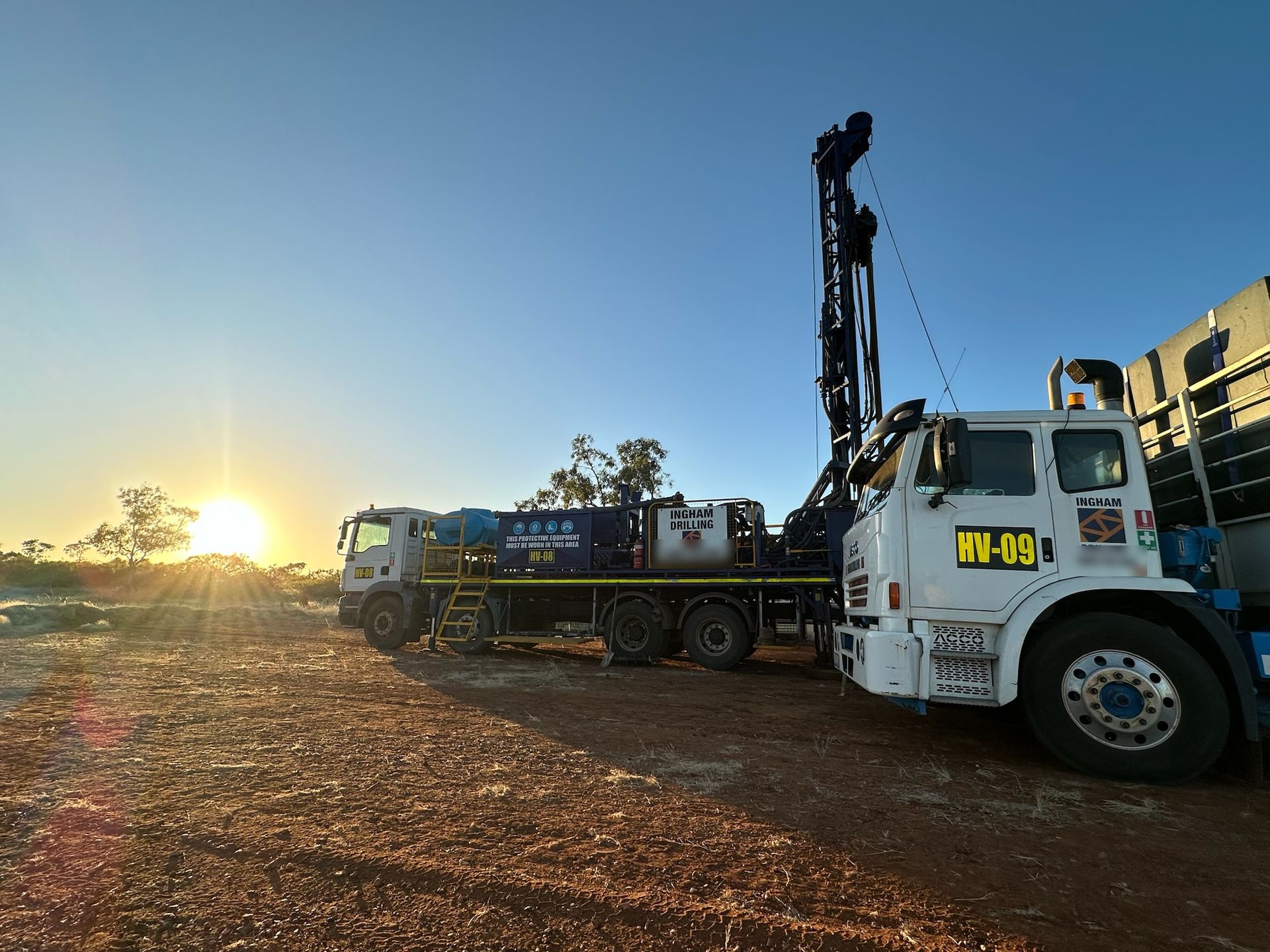 Sun rising behind rig HV-08, with support truck HV-09 in the foreground